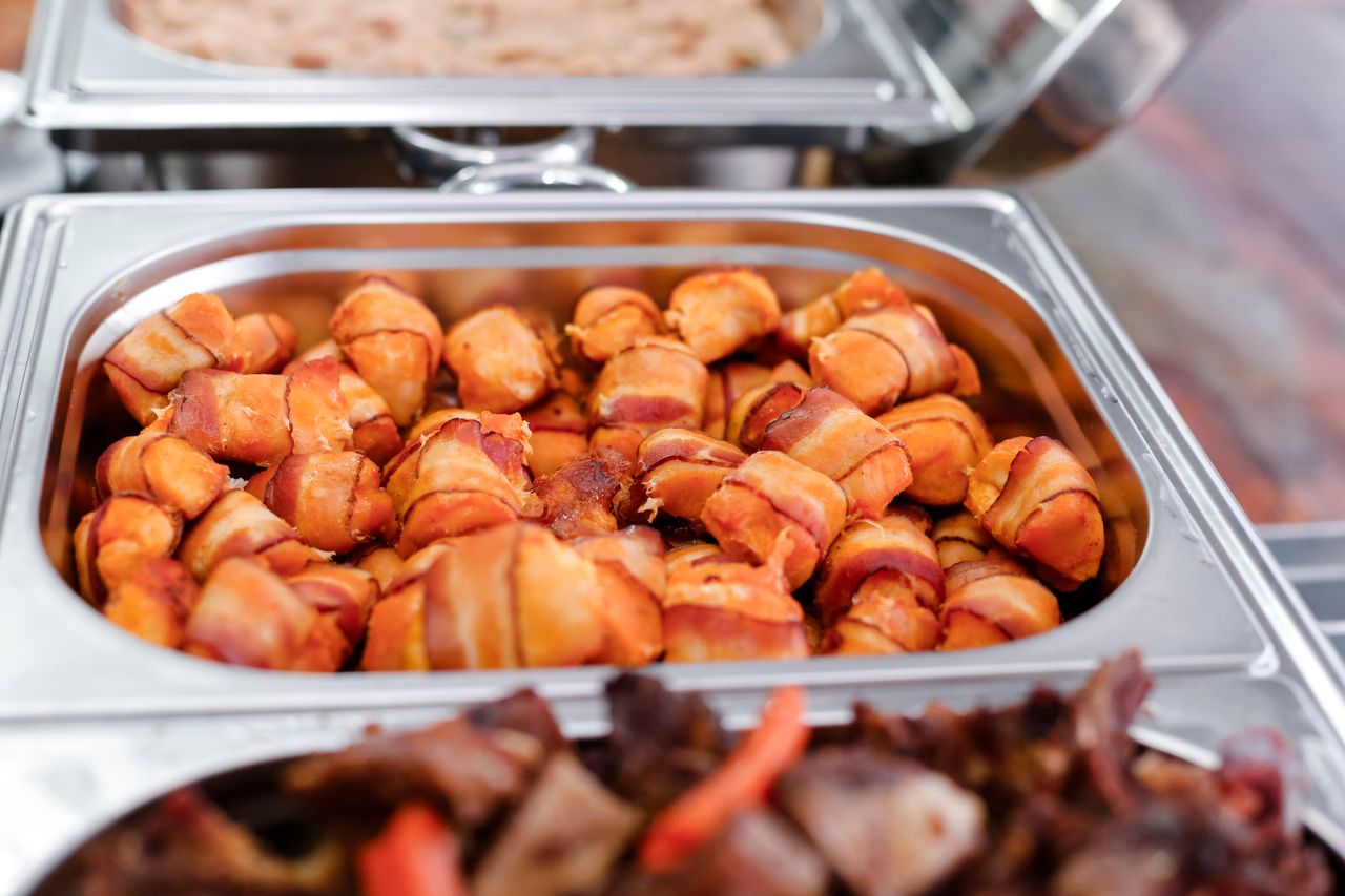 Delicious bacon wrapped appetizers ready to serve in a catering tray. Perfect for events.